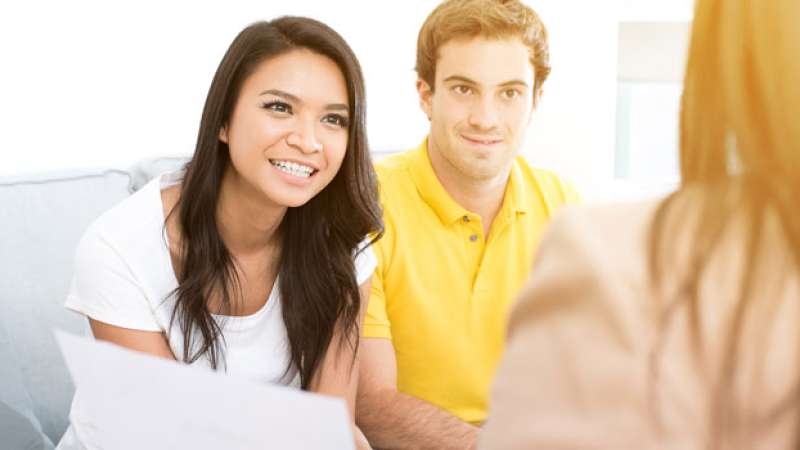 A husband and wife sit together with a financial aid counselor