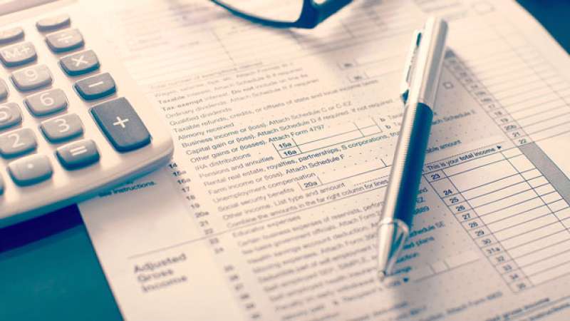 A calculator, pen, and an application are set out on a desk