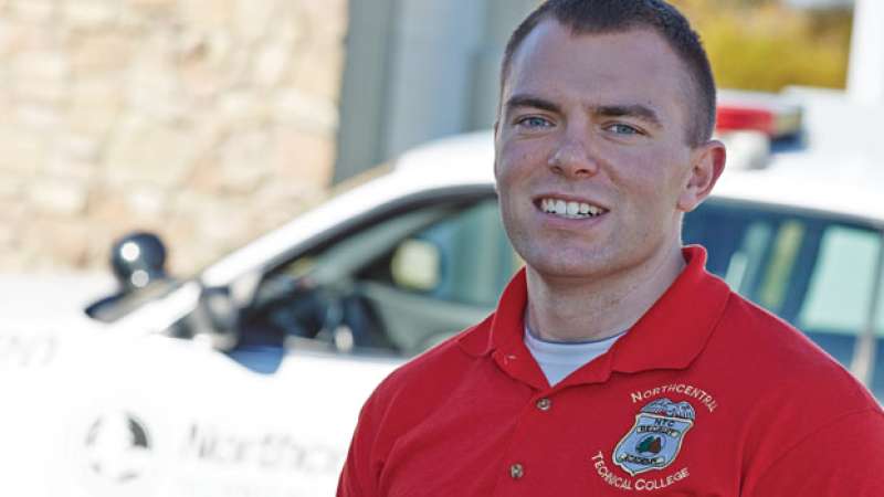 An NTC Security team member stands in front of a squad car