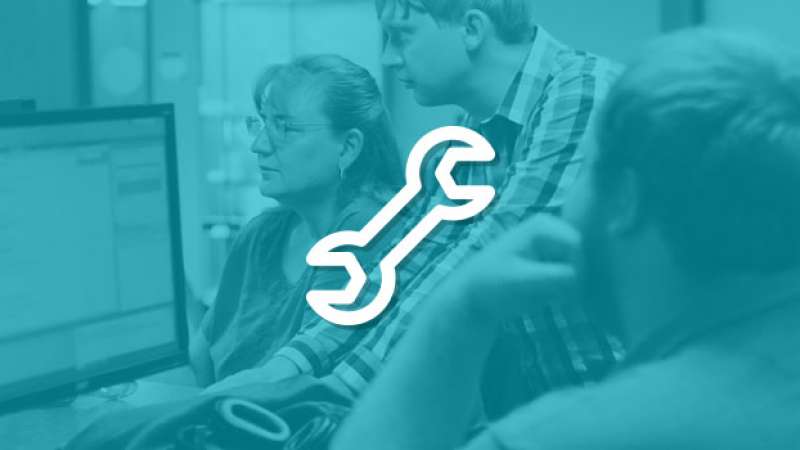 A symbol of a wrench is overlayed on top of an image of several helpdesk workers at NTC