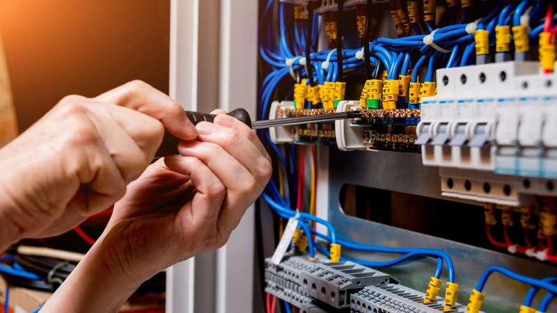 A student is tightening a screw holding a wire on a circuit board