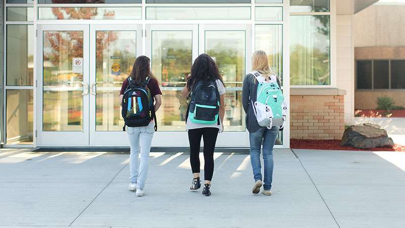 Three students with backpacks are walking into NTC together