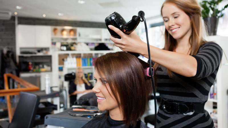 A cosmetologist styles her client’s hair.