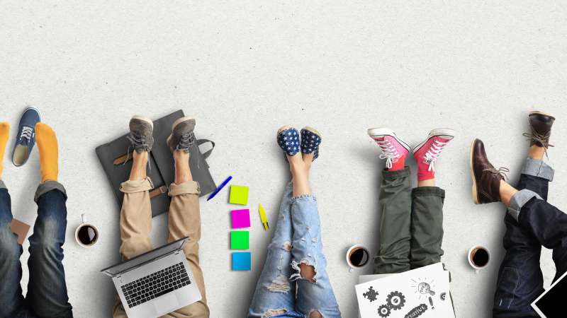 Legs and feet of students studying, with their materials on their laps and coffee mugs next to them.