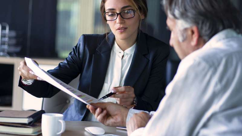 A woman in business attire reviewing a document with a client.