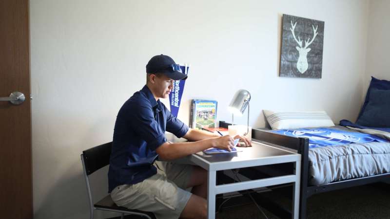 A student working at a desk in his room at Timberwolf Suites.