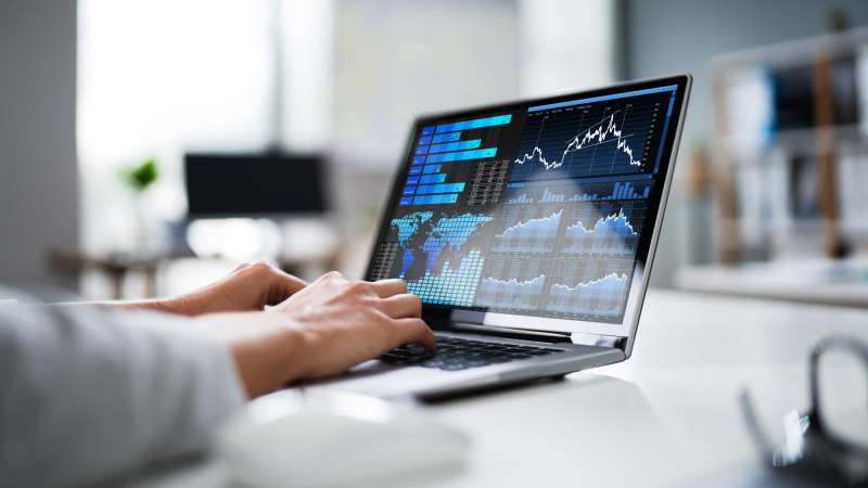 Someone using a laptop on a desk to analyze data using various charts and graphs.