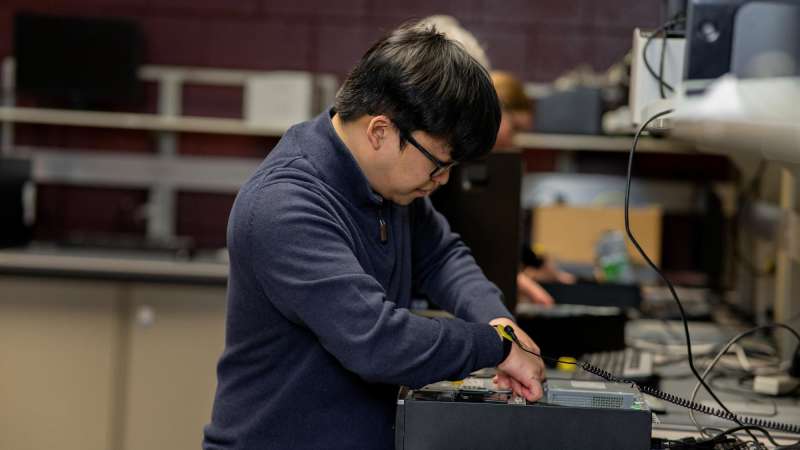 An IT Service Desk Technician with with an opened computer case troubleshoots a hardware issue.