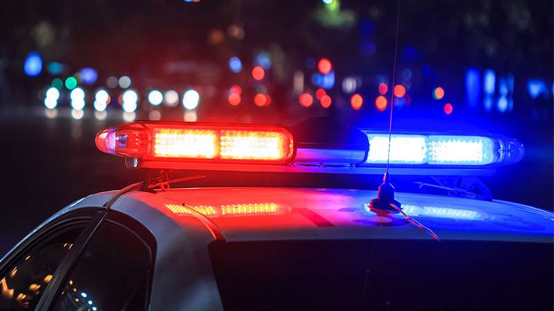 An external side view of a police car at night with the flashing lights turned on.