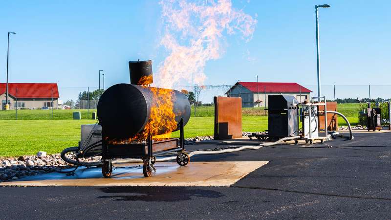 Natural gas supplies are hooked up to a black residential propane cylinder that is engulfed in flames.