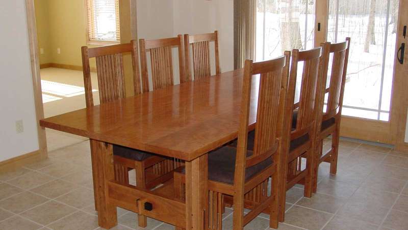 A custom wood dinette table and chairs sitting in a dining room of an otherwise unfurnished home.