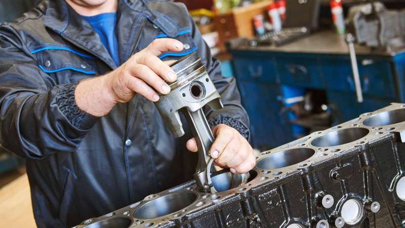 Diesel technician installing piston into engine