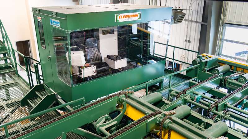 Elevated view of a green Cleereman control cab at Northcentral Technical College’s sawmill, featuring large observation windows, operator seating, and conveyor systems below.