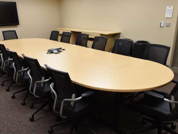 A conference room with one table lined by conference chairs on each side and at the ends.