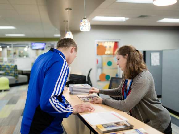 Staff member helps student find a program in a catalog.