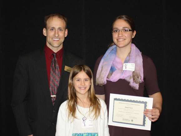 Brad Gast stands next to a student who received the Scott and Lucas Gast Scholarship. A young girl stands in front of them.