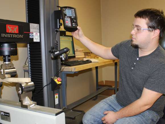 A student tests the strength of some wood using a machine.