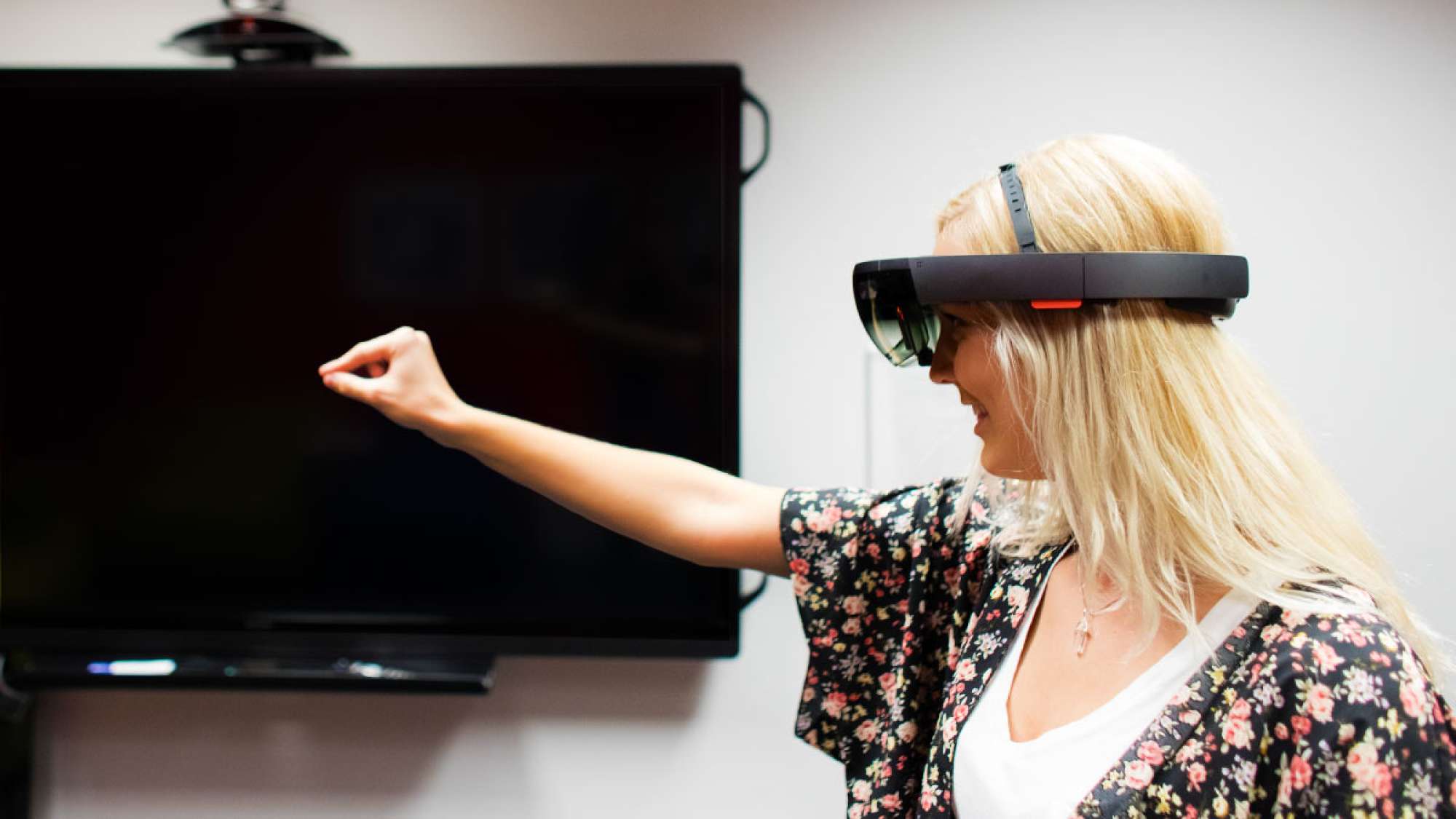 A student is using the Microsoft Hololens and reaching her out out to touch a virtual object only she can see.
