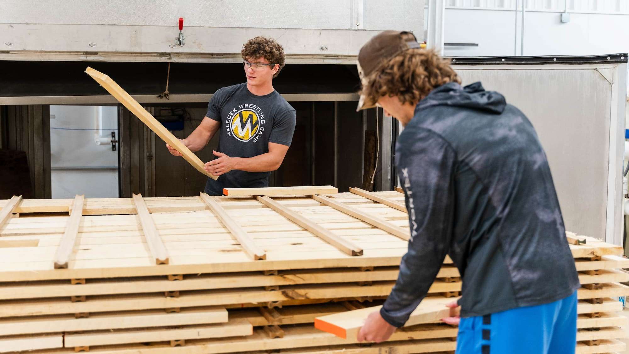 Two students examine lumber that is about to be moved into a kiln.