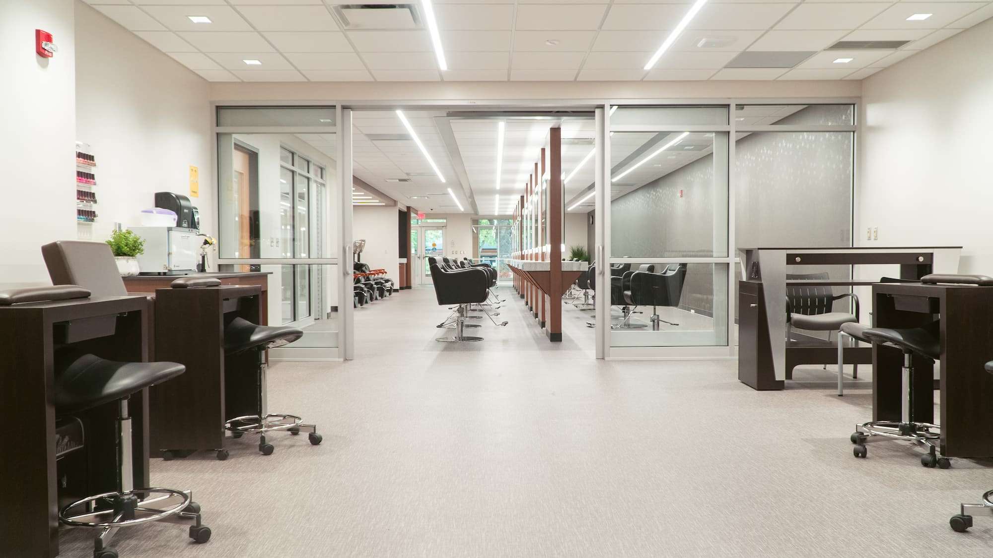 A view of NTC's Studio Max Salon, where students learn and practice cosmetology. The space is clean and brightly lit, featuring 20 styling stations, as well as shampoo stations, manicure/pedicure chairs,and facial tables.