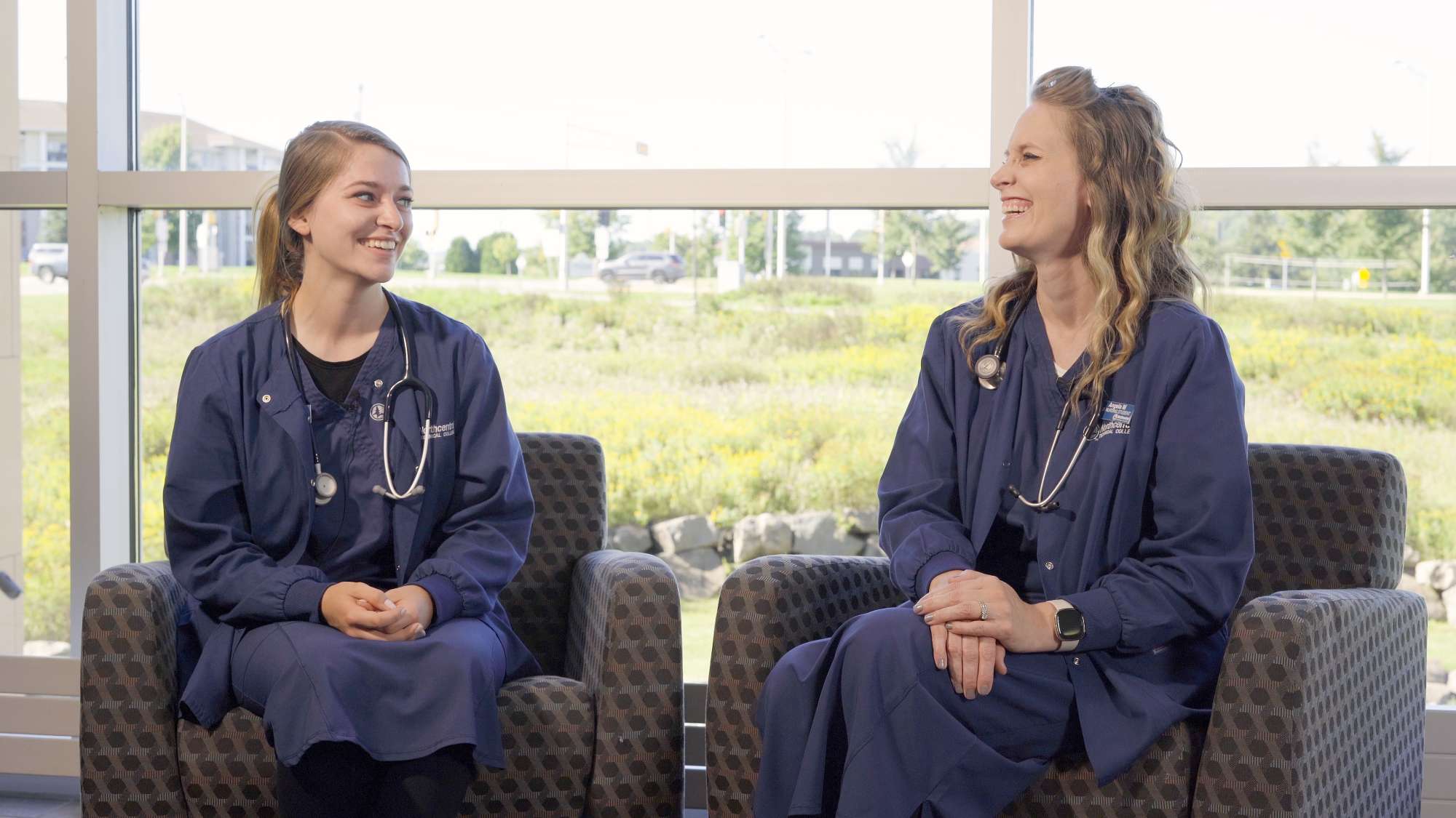 Two Nursing students, Jacquelynn and Angela Morrow, laughing and chatting while sitting near windows in the NTC Center for Health Sciences.