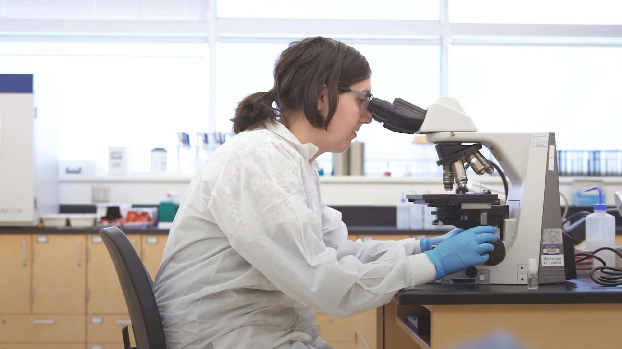 A student examines a sample under a microscope.