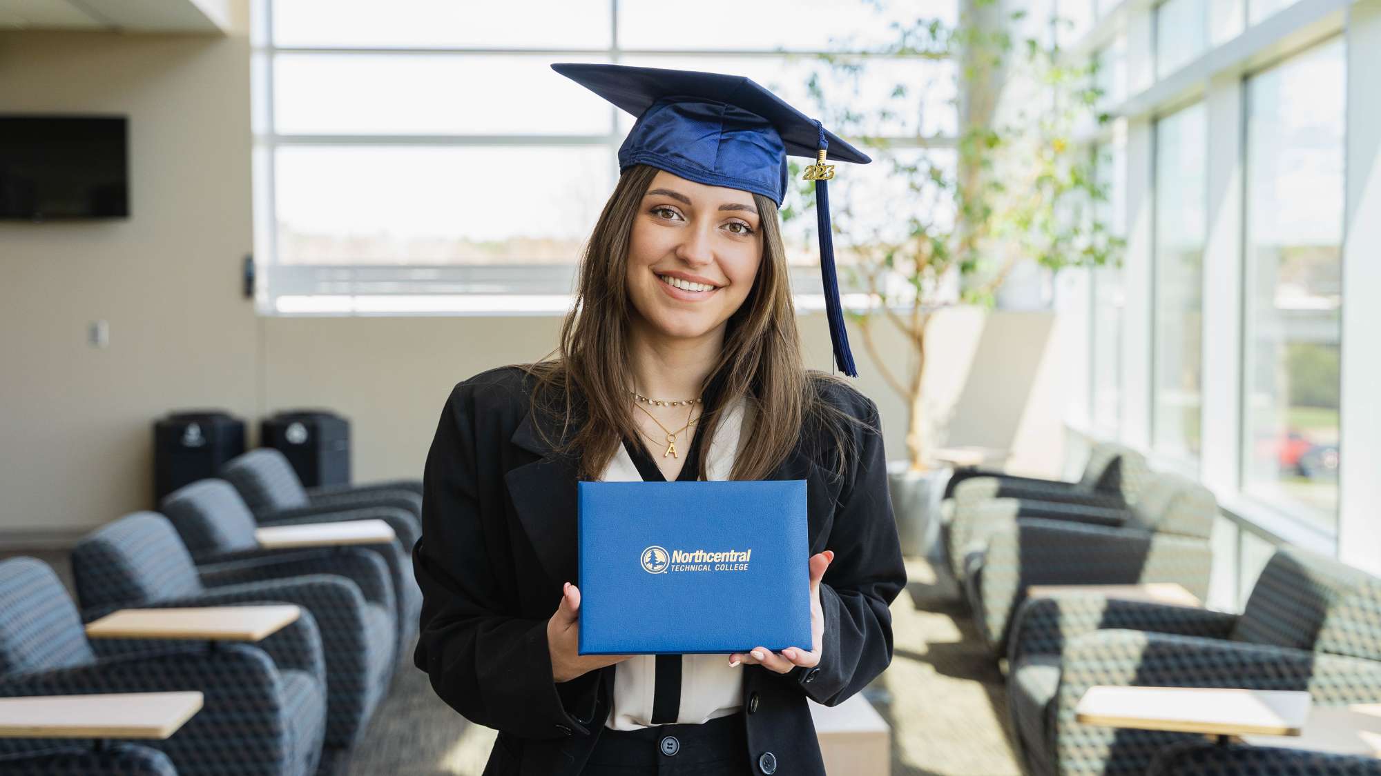 Arianna posing while wearing an NTC graduation cap and holding her diploma.