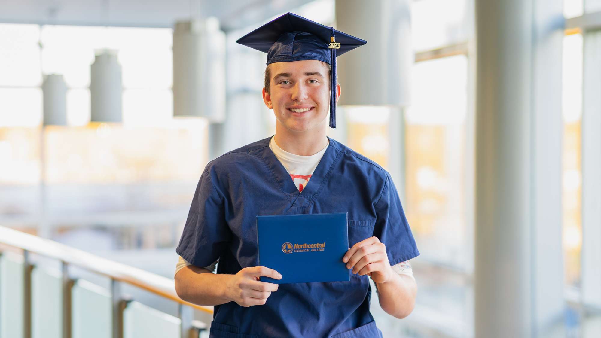 Dan'l posing while wearing an NTC graduation cap and holding his diploma.
