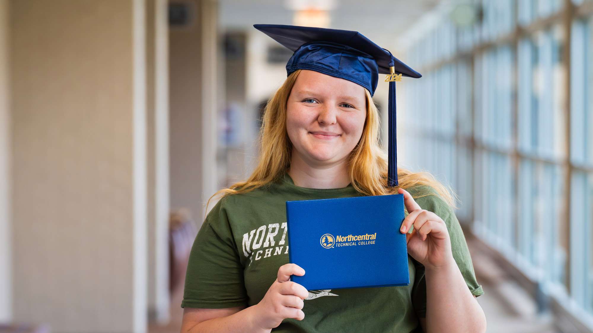 Grace Koehler posing while wearing an NTC graduation cap and holding his diploma.