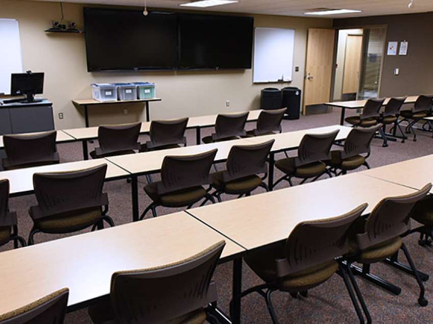 A training room with conference tables and chairs, as seen from the back of the room.