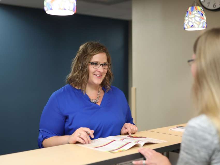 Woman stands at a lobby desk, getting information from a staff member.