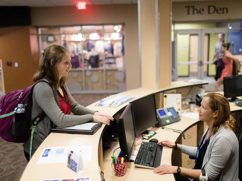 Student stands at the front desk of the Wausau Campus, as she talks to a staff member