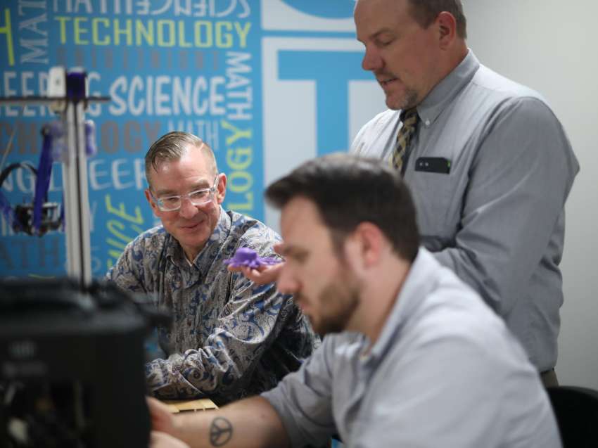 Two students, seated, listen to instructor explaining something.