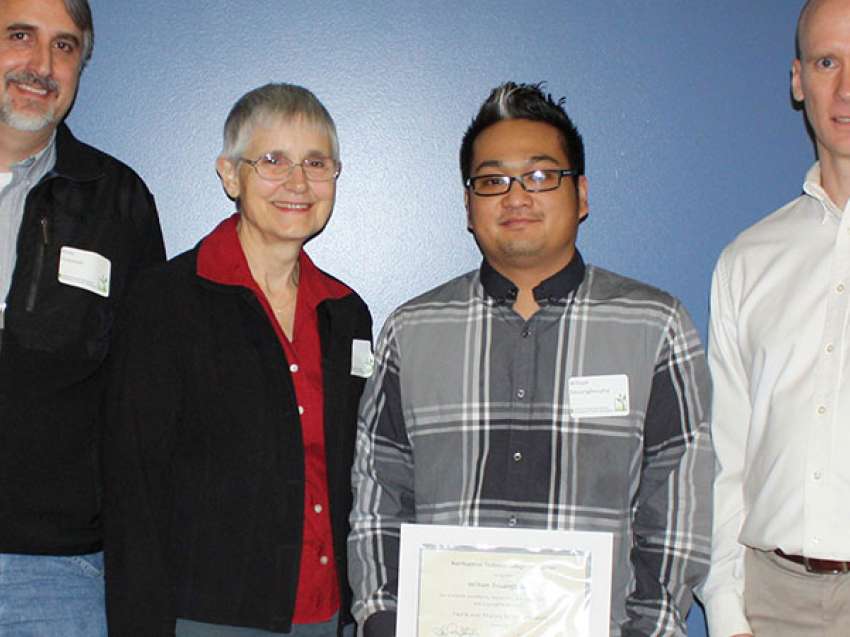 Three people present a scholarship to a student