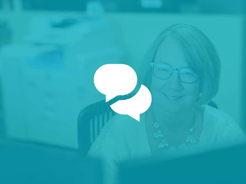 A receptionist sitting at her desk, smiling, while looking at her monitors.