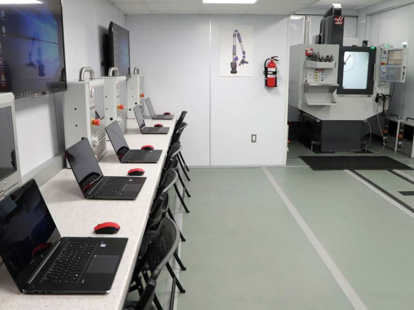 Several laptops and other equipment sitting on a table along the wall in the Advanced Manufacturing Mobile Lab