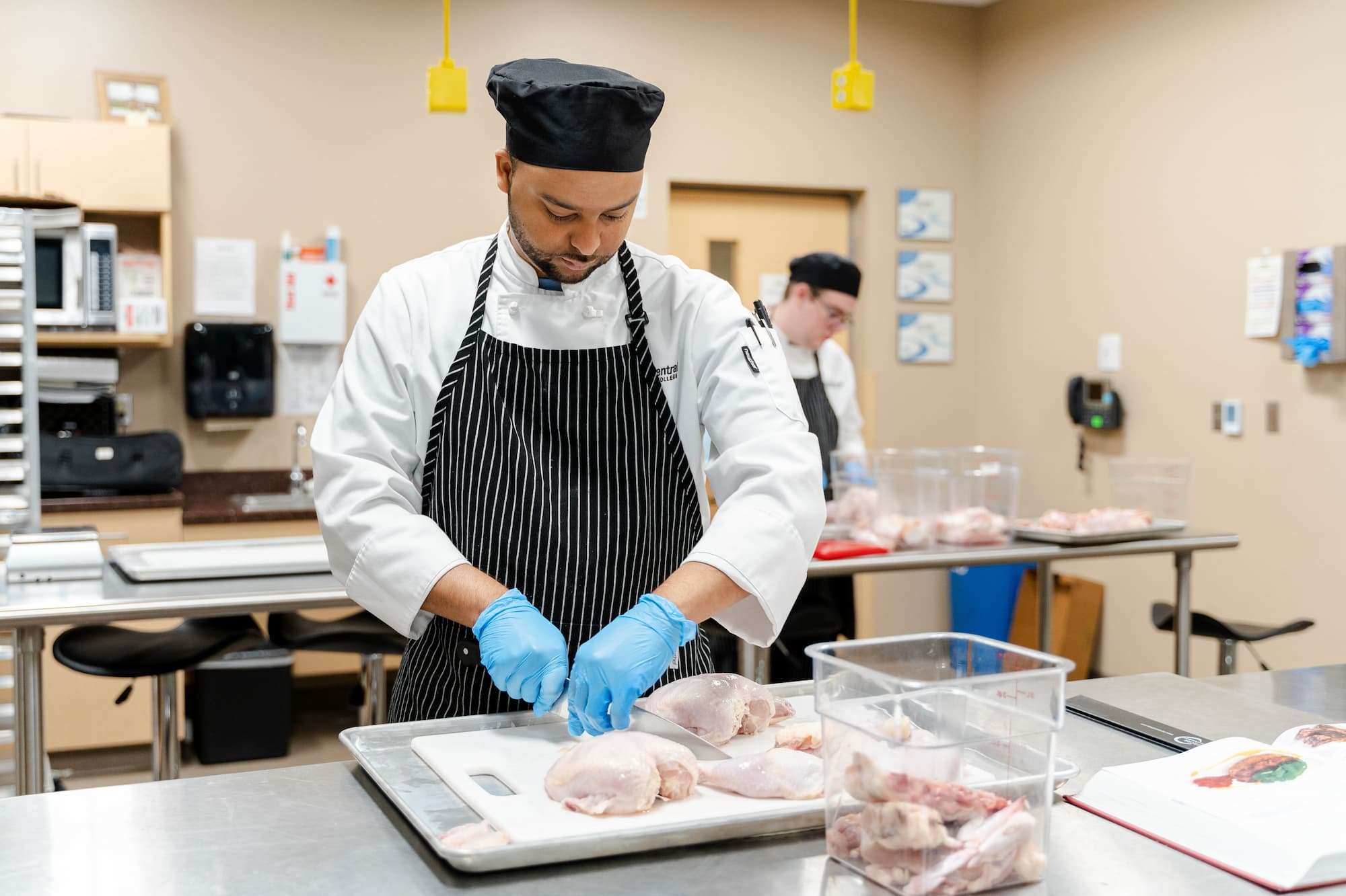 A whole chicken is cut and divided into clean pieces by a student.