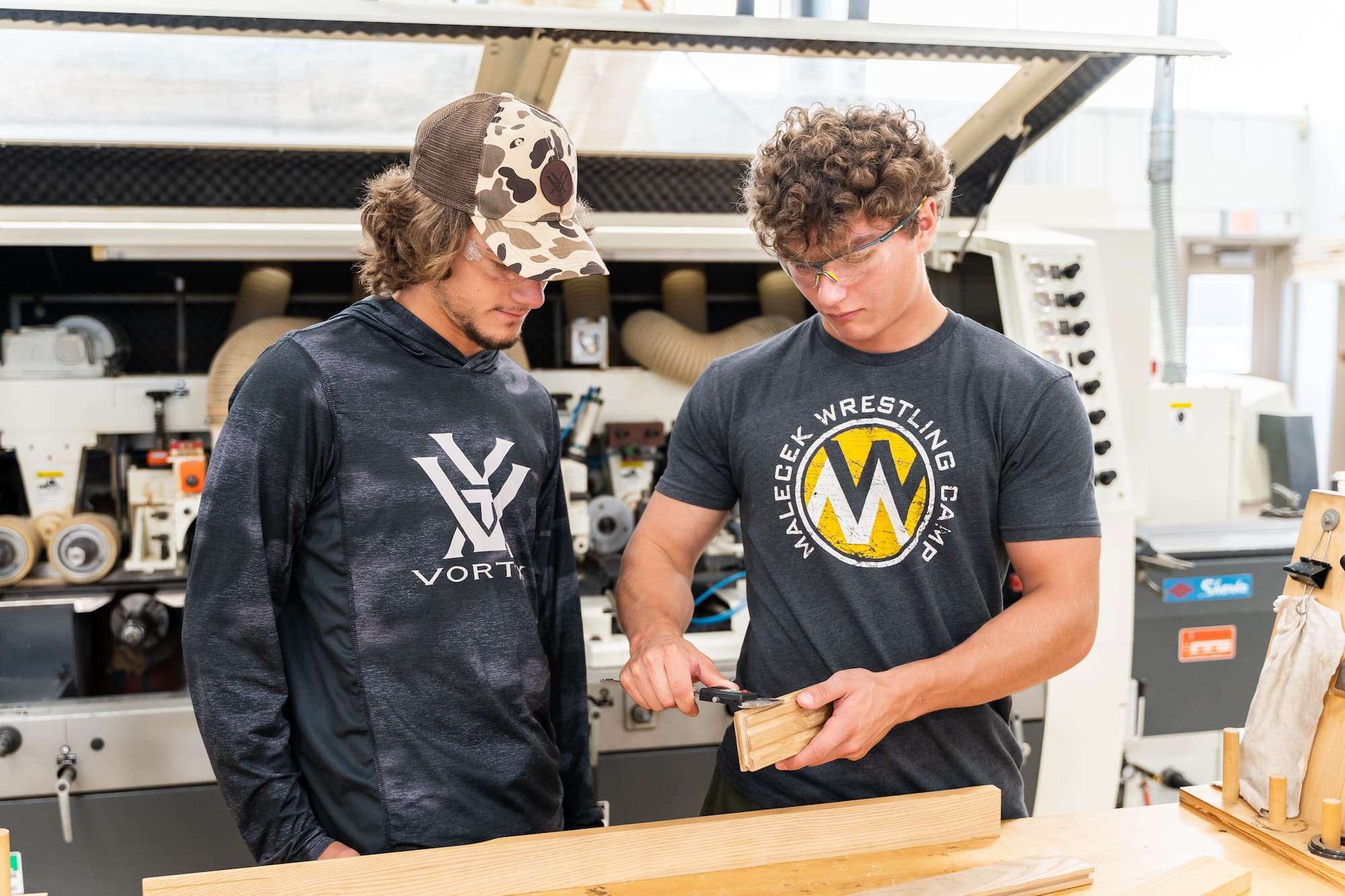 After lumber has passed through a moulder, two students measure the resulting cuts with a micrometer.