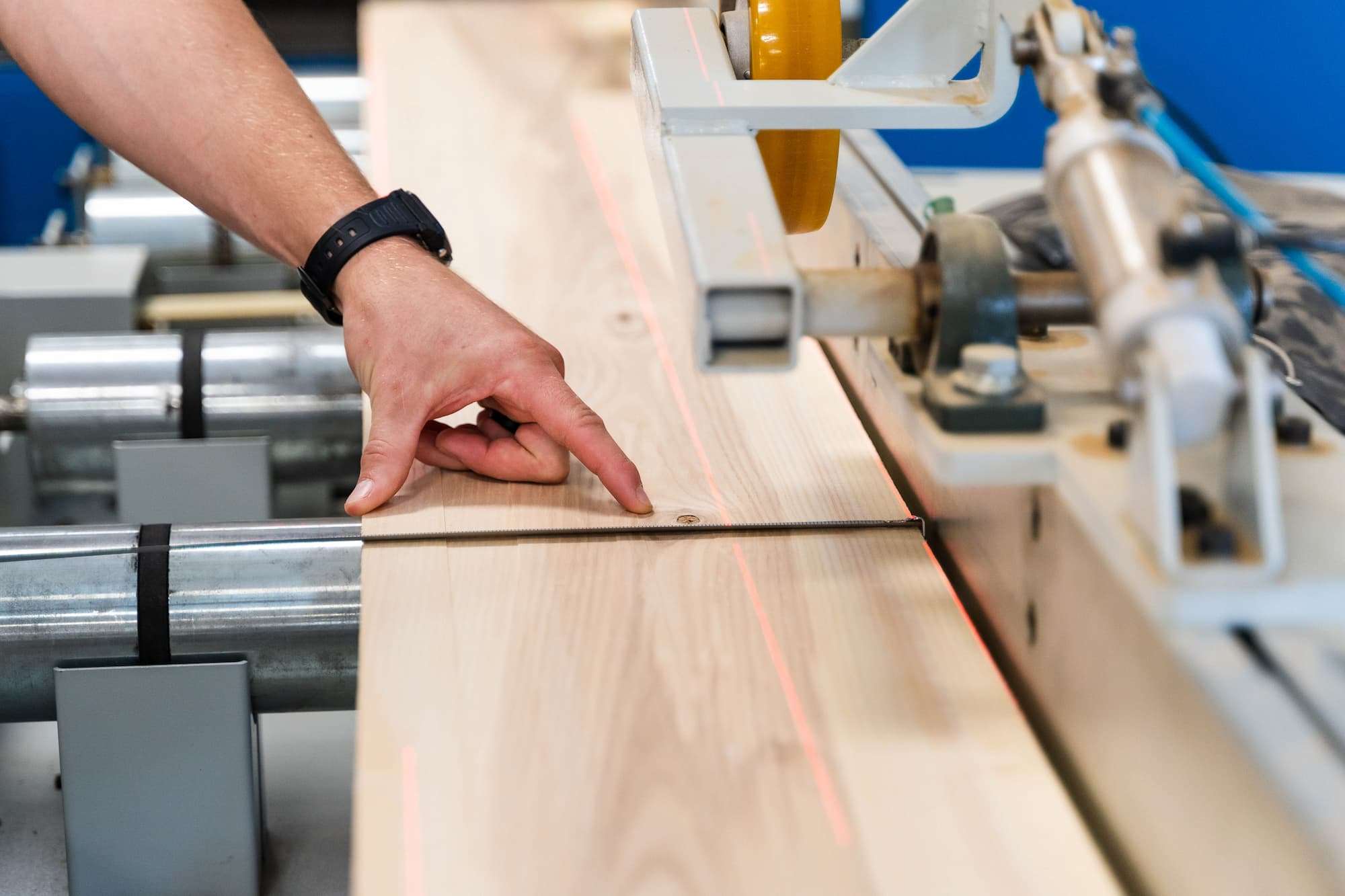 A close-up of lumber passing through a roughing mill, marked by a red laser line.