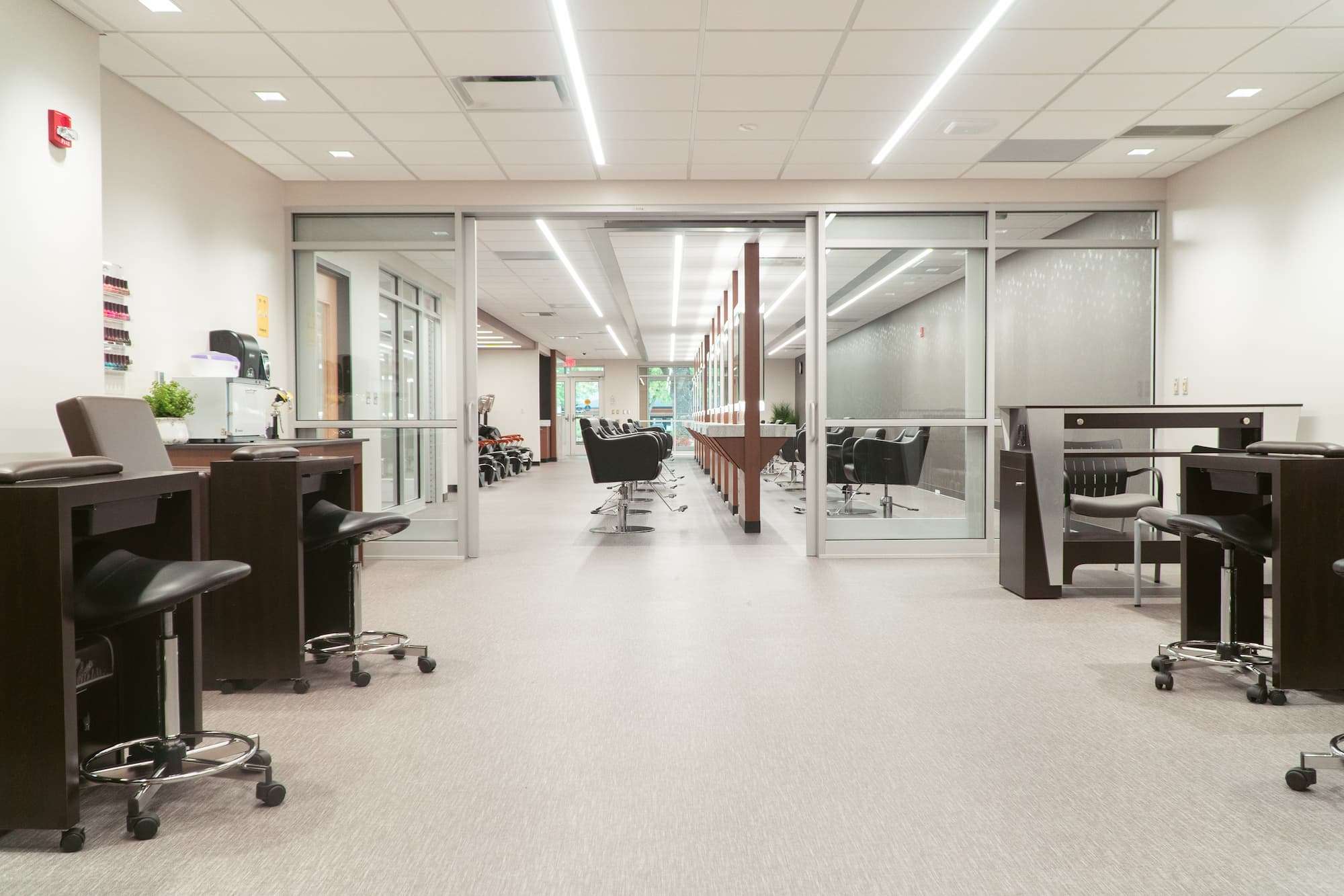 A view of NTC's Studio Max Salon, where students learn and practice cosmetology. The space is clean and brightly lit, featuring 20 styling stations, as well as shampoo stations, manicure/pedicure chairs,and facial tables.