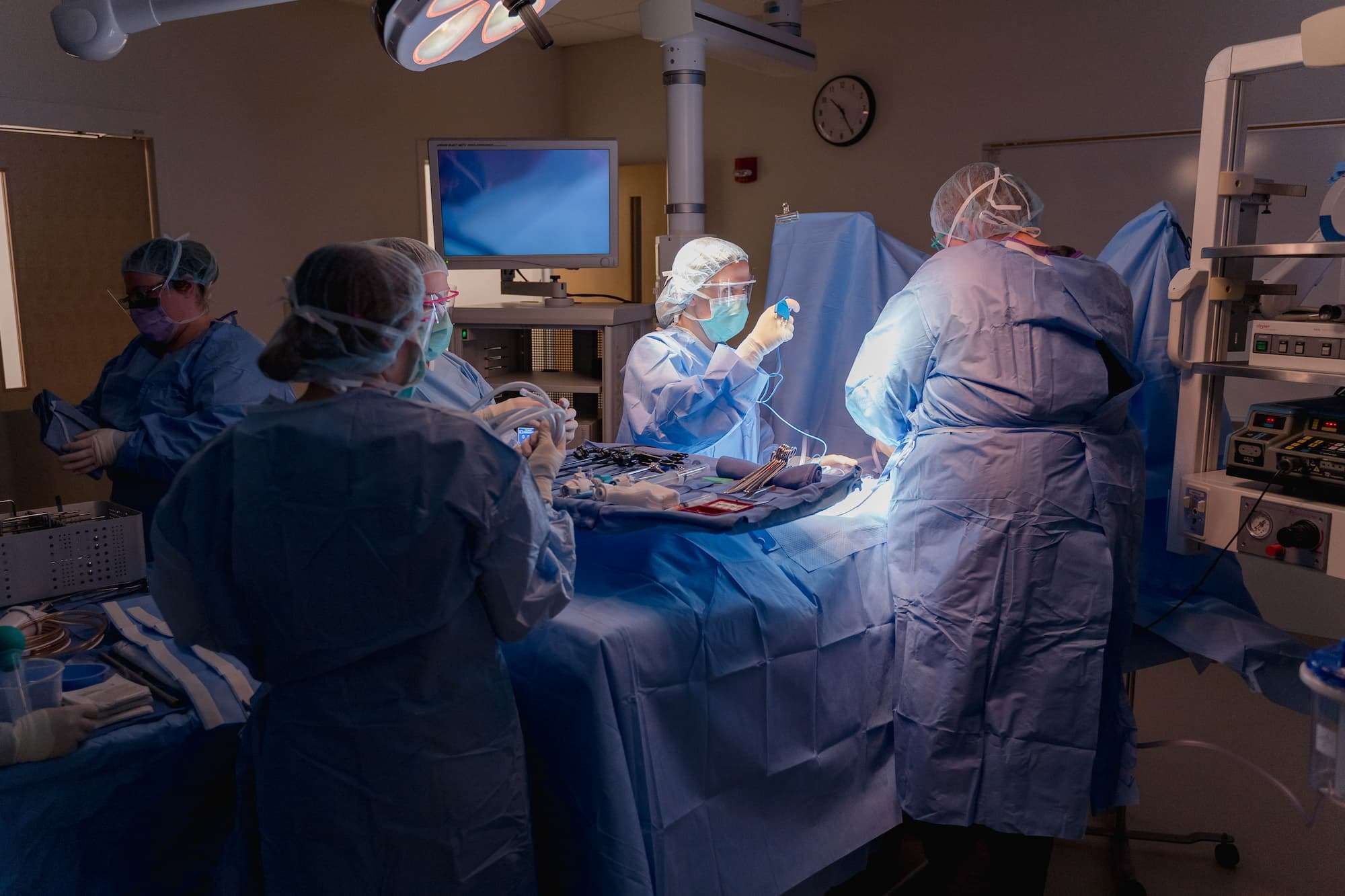 With a surgical lamp positioned to illuminate a mannequin, a group of students begin a mock operation.