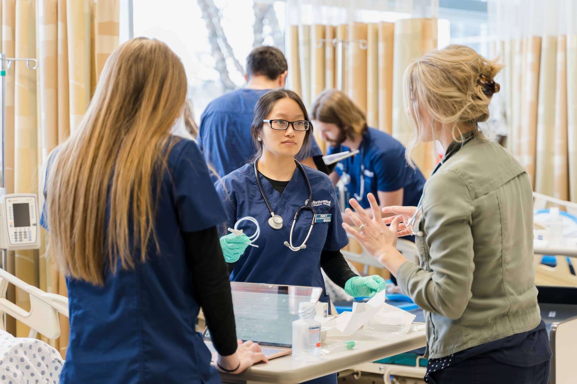 An instructor checks in with two nursing students to answer questions.