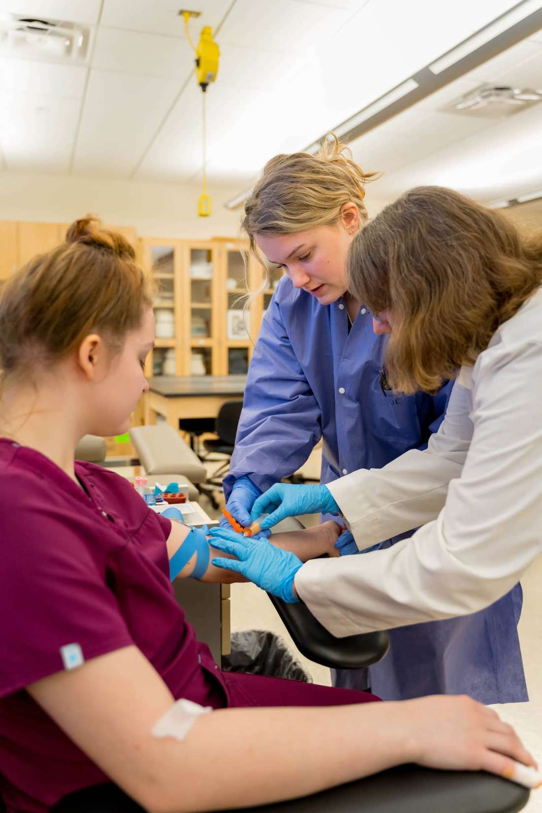 An instructor works with a student to demonstrate proper placement and technique with a syringe.