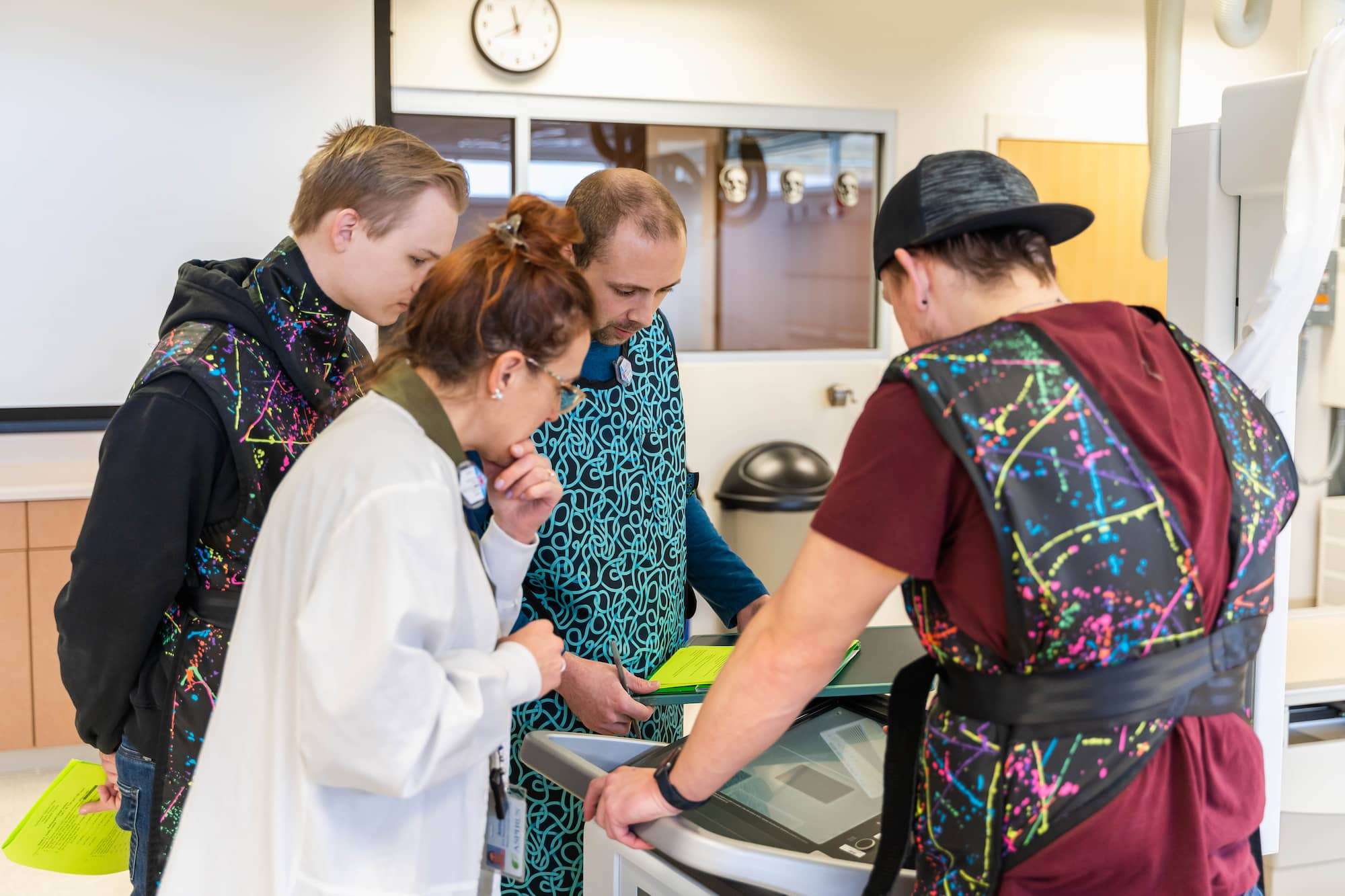 A group of students with their instructor huddle over imaging displays to review their findings.