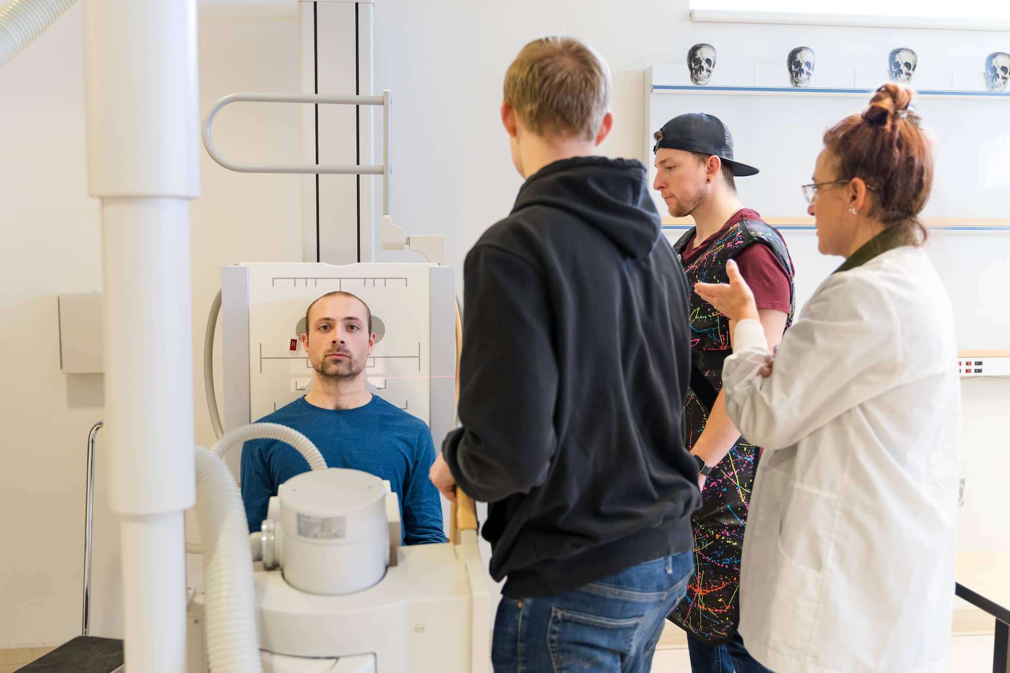 A student acts as the patient while their classmates prepare to conduct imaging of the skull.