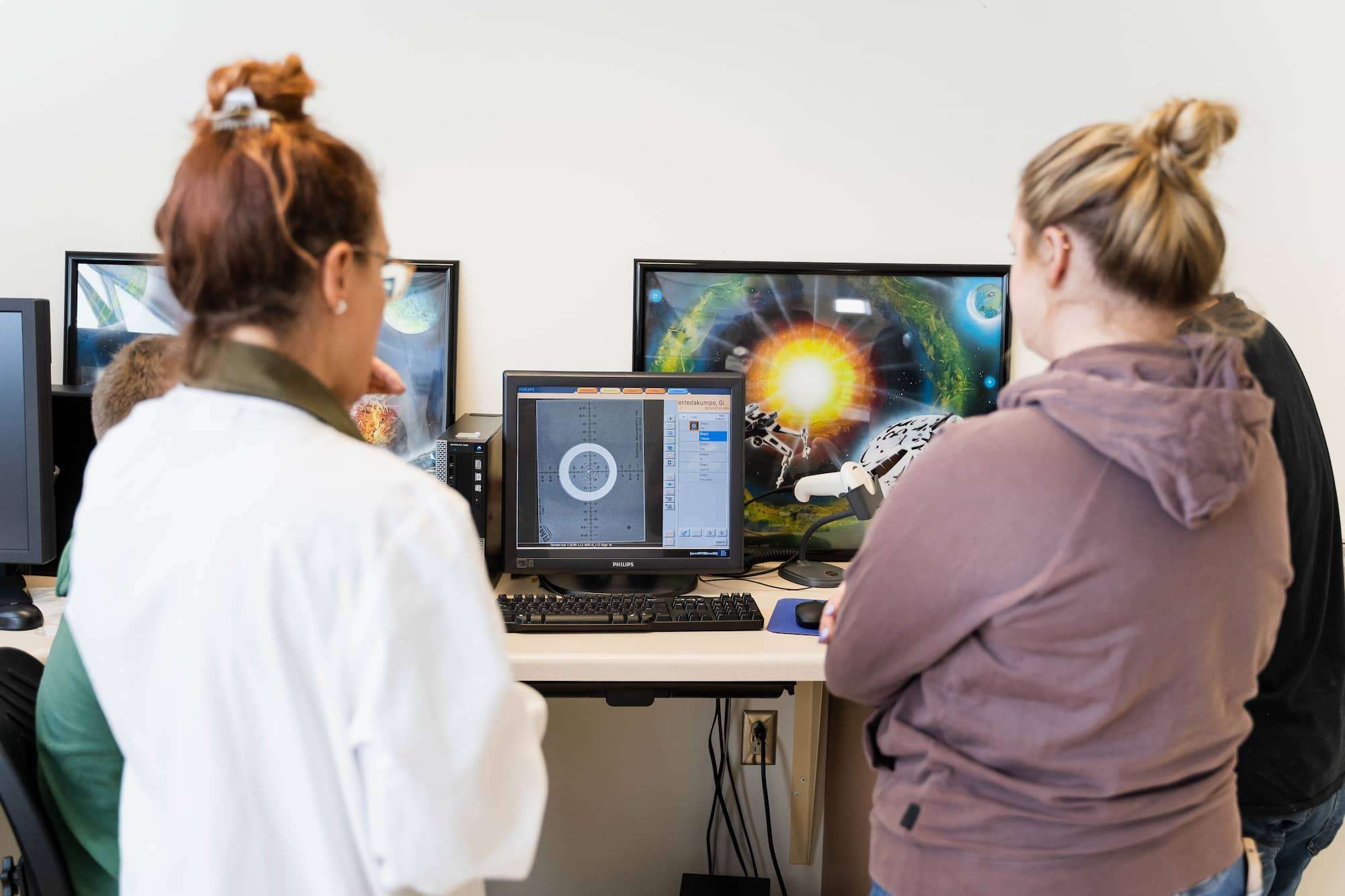 Students and instructor look on at an array of monitors with diagnostic information.