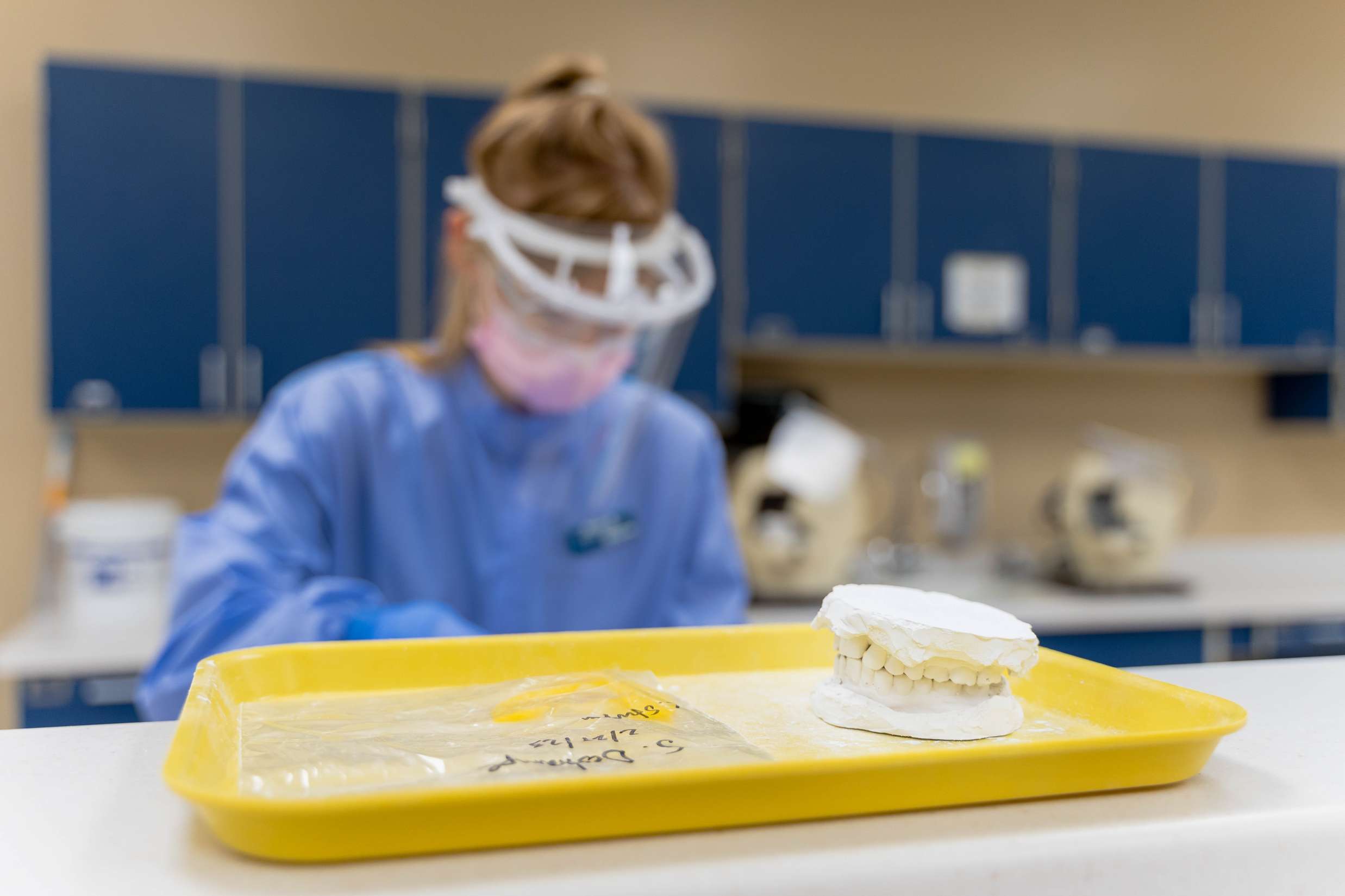 A mold of a patients top and bottom teeth is set out on a tray in front of a dental hygienist.
