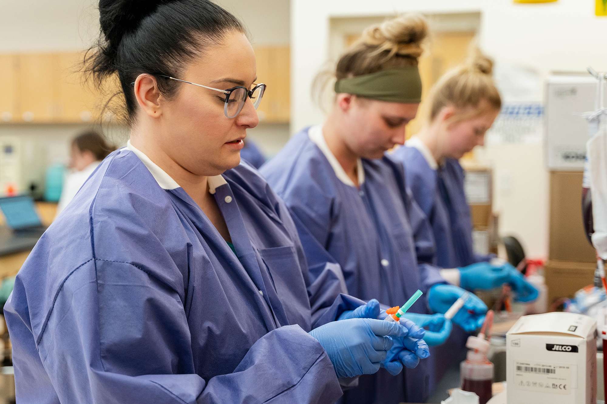 Three Medical Assistants are working next to each other in a lab while checking blood work.