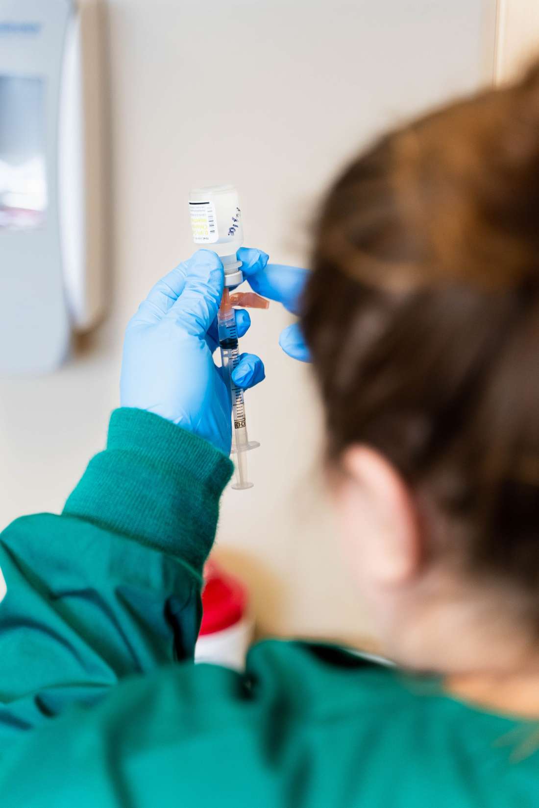 A Medical Assistant uses a syringe to collect medicine from a vial.