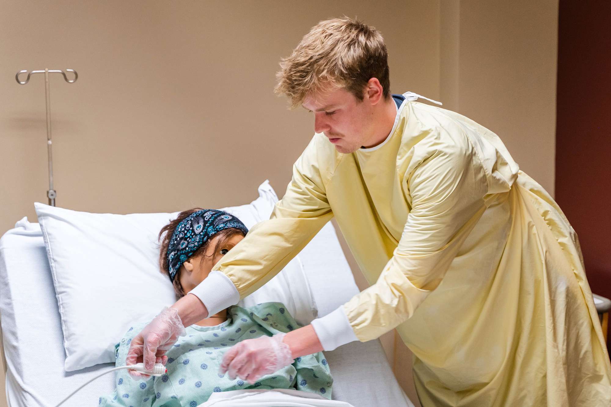 A Nursing Assistant is setting up medical diagnostic cables on a medical mannequin.